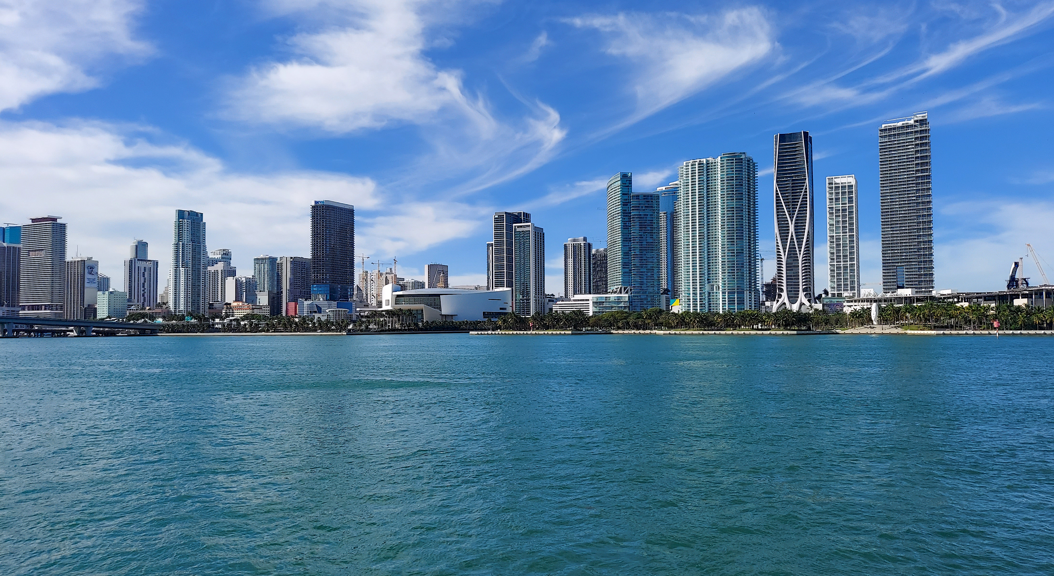 Daytime downtown Miami skyline across Biscayne Bay, framed with decorative palm silhouettes